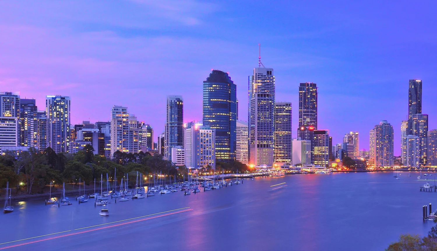 Brisbane city skyline at dusk with buildings and river.