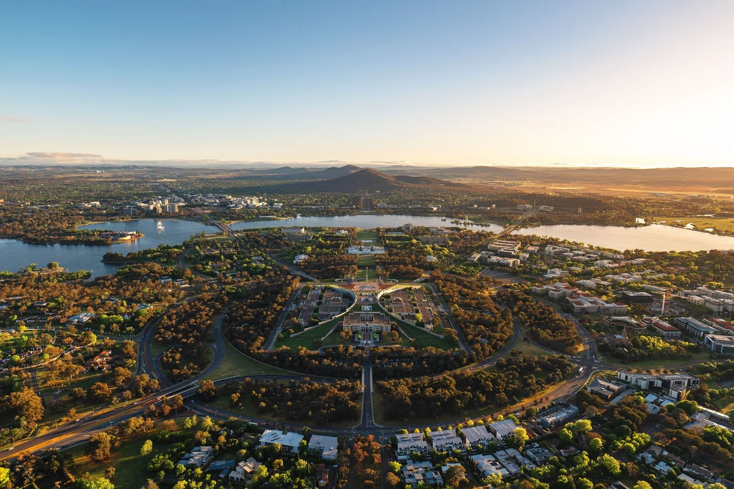 Aerial view of Canberra, Australia, featuring Lake Burley Griffin, central cityscape, and surrounding greenery.
