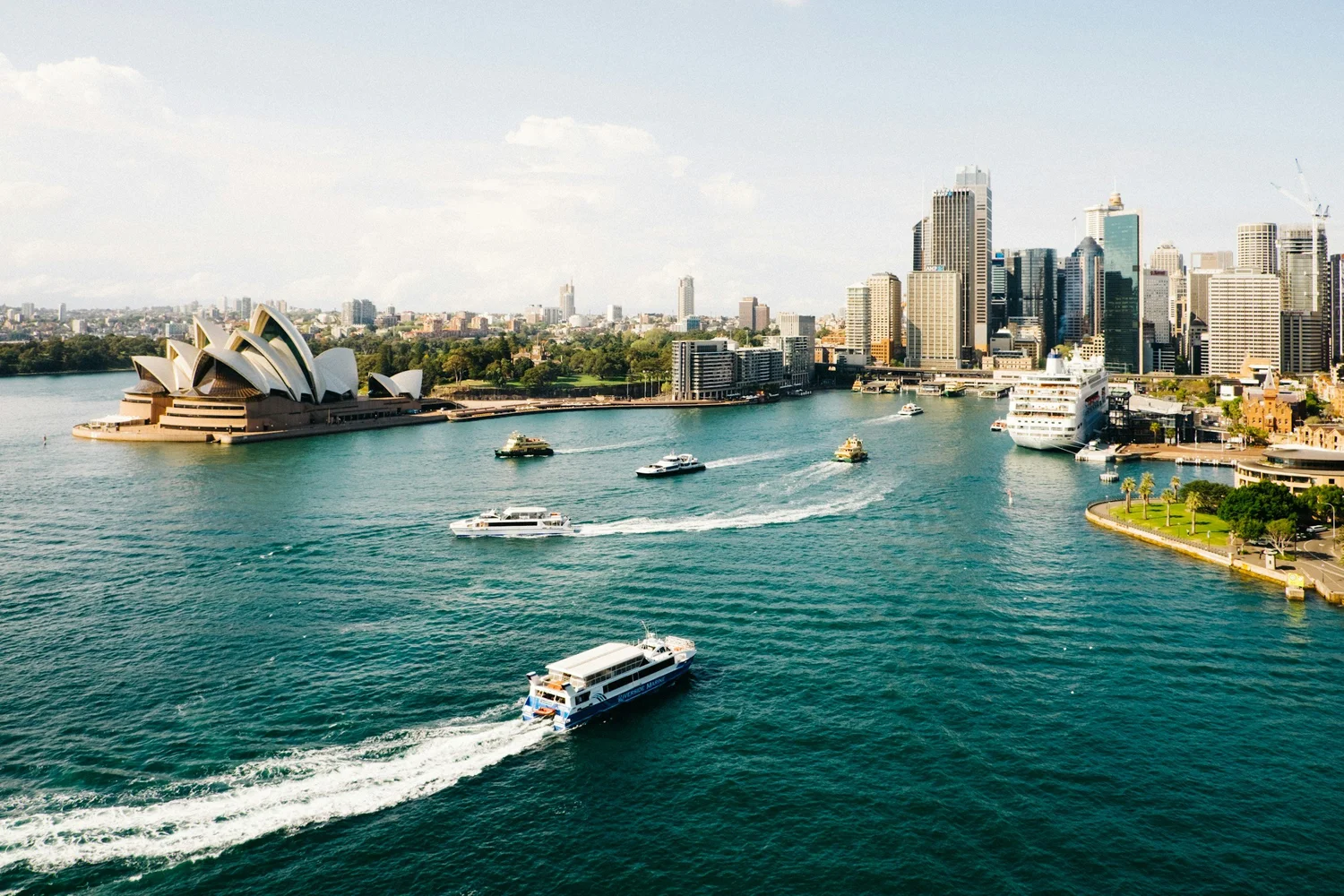 Aerial view of Sydney Opera House and Sydney Harbour, with boats and city skyline.