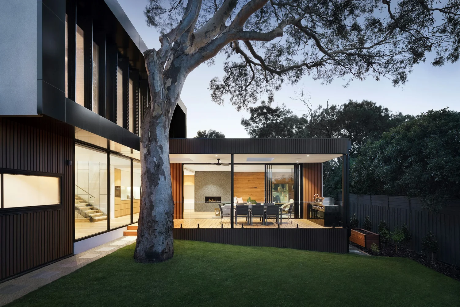 Modern house with outdoor patio and large tree in front yard